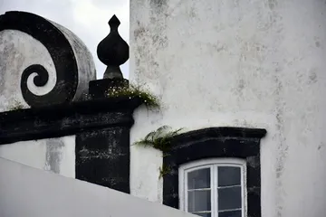 A black and white building with a window and a balcony.