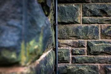 Black metal fence near gray concrete wall.